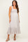 woman wearing a light gray smocked maternity dress with ruffle hem and wide straps, showcasing a baby bump