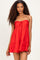 woman wearing a red strapless sundress with a tie front and ruffled hem