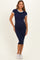 woman wearing a navy blue maternity dress with white trim and a visible baby bump, styled with white sneakers