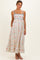 woman wearing a floral print maternity maxi dress with blue straps and pockets, showcasing her baby bump