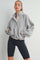woman wearing a grey fleece pullover with a high collar and snap buttons, paired with black bike shorts