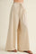 woman wearing beige wide-leg linen pants with a drawstring waist and pleated details