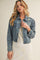 woman wearing a distressed light blue denim jacket over a white lace dress