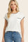 woman wearing a white short sleeve top with black trim and a chest pocket, paired with blue jeans
