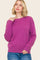 woman wearing a vibrant pink oversized sweater with a round neckline and relaxed fit, paired with blue jeans