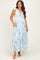 woman wearing a light blue floral maternity dress with ruffle sleeves and pockets, showcasing her baby bump