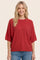 woman wearing a red oversized short sleeve sweater with a relaxed fit and smiling