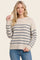 woman wearing a cream and navy striped sweater with long sleeves and a round neckline, paired with blue jeans