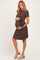 woman wearing a brown short sleeve maternity dress with a tie detail, gently cradling her baby bump