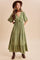 woman wearing a green maxi dress with puff sleeves and a tie front, styled with a wide-brim hat and brown ankle boots