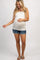 woman wearing a teal short sleeve maternity top and denim shorts, showing her baby bump
