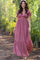 woman wearing a pink floral maxi dress with short puff sleeves and a tiered skirt, walking outdoors in a garden setting