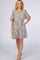 woman wearing a short beige dress with black spots and flounce sleeves