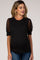 woman wearing a black maternity top with sheer polka dot puff sleeves and blue jeans