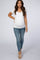 woman wearing a white short sleeve maternity top and distressed blue skinny jeans, showing her baby bump