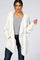 woman wearing a white fuzzy open front cardigan over a grey shirt and dark blue jeans