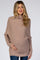 woman wearing a light taupe oversized maternity sweater, gently holding her baby bump