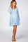 woman wearing a light blue polka dot maternity dress with a smocked bodice and long sleeves, showing her baby bump