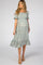 woman wearing a light blue floral print maternity dress with short sleeves and a tiered skirt, baby bump visible