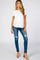 woman wearing a white short sleeve maternity top and distressed blue skinny jeans, with a subtle baby bump visible