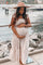 pregnant woman in beige maxi dress and wide brim hat holding her baby bump by a waterfront pier
