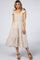 woman wearing a light beige smocked midi dress with tie shoulder straps and a tiered skirt