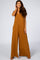 woman wearing a camel colored wide leg maternity jumpsuit with spaghetti straps and pockets