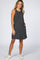 woman wearing a black and white striped sleeveless maternity dress with pockets and white sneakers