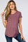woman wearing a mauve short sleeve maternity top with a curved hem and a relaxed fit, holding her hair back