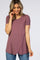 woman wearing a mauve short sleeve top with an asymmetrical hem, paired with blue jeans