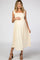woman wearing a cream-colored maternity dress with tie straps and a visible baby bump