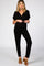 woman wearing a black maternity jumpsuit with a v-neckline and a relaxed fit, showcasing her baby bump