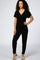 woman wearing a black short sleeve wrap jumpsuit with a tie waist and relaxed fit