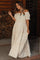 woman wearing a cream off-shoulder maternity maxi dress with tiered ruffles and a decorative neck scarf