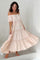 woman wearing a light pink off-the-shoulder maxi dress with tiered ruffles and flowing silhouette