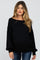 woman wearing a black off-the-shoulder maternity sweater with long sleeves and a relaxed fit, showcasing her baby bump