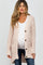 pregnant woman wearing a light pink popcorn knit maternity cardigan over a white top and blue jeans