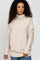 woman wearing a beige oversized turtleneck sweater with long sleeves and a relaxed fit