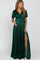 woman wearing a dark green maternity wrap dress with short sleeves and a thigh-high slit, holding her baby bump
