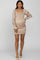 woman wearing a beige maternity mini dress with ruched details and long, puffy sleeves, displaying her baby bump