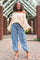 woman wearing a cream oversized off-the-shoulder sweater and light blue cargo jeans with side pockets and heeled sandals