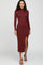 woman wearing a burgundy long sleeve midi dress with a turtle neck and a side slit