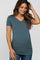 woman wearing a teal v-neck maternity top with ruching, showing her baby bump, paired with jeans
