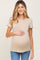 woman wearing a beige short sleeve maternity top and holding her baby bump