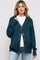 woman wearing a dark teal cardigan with buttons over a white t-shirt and light blue jeans, no visible baby bump
