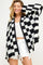 woman wearing a black and white checker patterned oversized cardigan over a white crop top and denim shorts