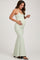 woman wearing a light green maternity maxi dress and holding her baby bump