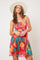 woman wearing a colorful floral print sundress with a fitted bodice and flowy skirt, accessorized with a wide-brimmed hat