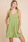 woman wearing a green sleeveless romper with tie straps and side pockets
