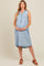 woman wearing a light blue sleeveless denim maternity dress and cradling her baby bump